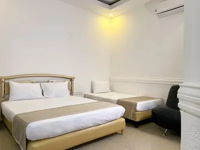a hotel room with two beds and a chair at Hotel Barranquilla Prado in Barranquilla