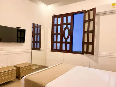 a bedroom with a bed and a tv and a window at Hotel Barranquilla Prado in Barranquilla