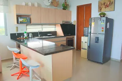 a kitchen with a refrigerator and two orange chairs at Magico Apartamento Frente al Mar 3 Habitaciones PV81 in Coveñas
