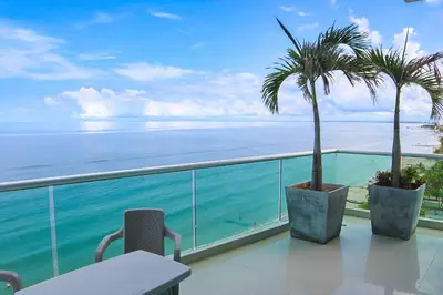 a balcony with a table and palm trees and the ocean at Magico Apartamento Frente al Mar 3 Habitaciones PV81 in Coveñas