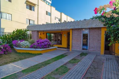 a building with purple flowers in front of it at Colonial Beach Airport Hotel in Cartagena de Indias