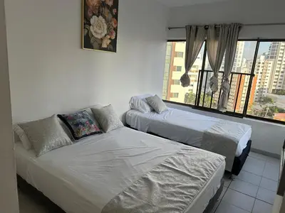 two beds and a couch in a room with a window at BARLOVENTO in Cartagena de Indias
