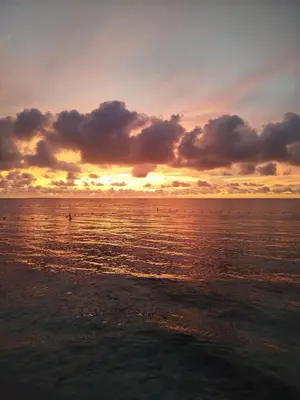 a sunset over the ocean with a person in the water at Mi Cabañita Guest House in Playa Blanca