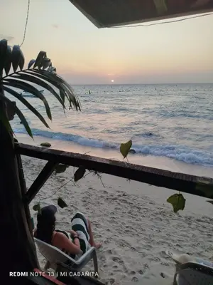 a couple sitting in a chair on the beach at Mi Cabañita Guest House in Playa Blanca