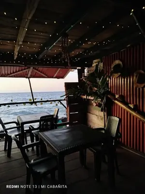a patio with tables and chairs and the ocean at Mi Cabañita Guest House in Playa Blanca