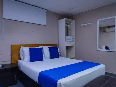 a bedroom with a bed with blue and white pillows at Hotel Casa Boston Inn by Finerh in Barranquilla