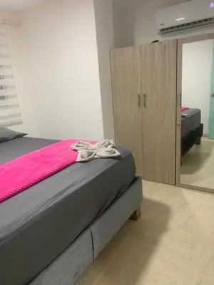 a bedroom with a bed with a pink blanket and a cabinet at Apartamento en la Boquilla in Cartagena de Indias