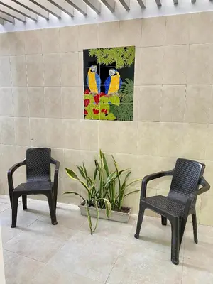 two chairs and a painting of parrots on a wall at Guakmaya hostel in Cartagena de Indias