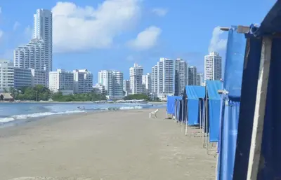 a row of blue beach huts on the beach at Habitación para 3 a una cuadra de la playa y bahía in Cartagena de Indias