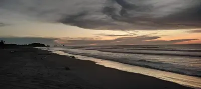 a beach with a cloudy sky and the ocean at Hostal torres del caribe in San Bernardo del Viento