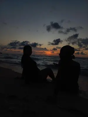 two people sitting on the beach watching the sunset at Hugos Place Baru in Playa Blanca