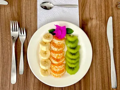 a plate of food with bananas and kiwi slices at Charme 64 Hotel Boutique in Cartagena de Indias