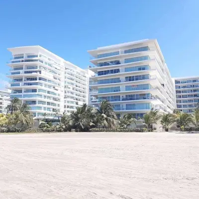 two tall buildings with palm trees in front of a beach at Apartamento Cartagena Morros Epic in Cartagena de Indias