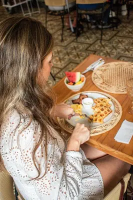 a woman sitting at a table with a plate of food at Casa Noa Colonial Rooms in Cartagena de Indias