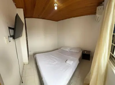 a small bedroom with a white bed and a television at Apartamento VIVAMAR Manantial in Cartagena de Indias