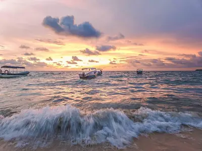 two boats in the water at a beach at sunset at Apartamento Edificio los Delfines Bocagrande , ubicación y precio in Cartagena de Indias