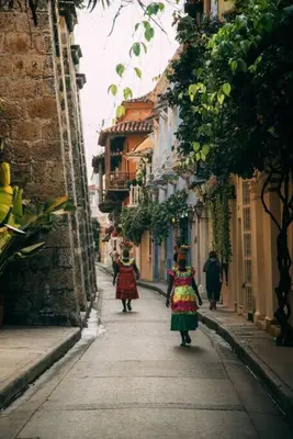 two women walking down a narrow street with buildings at Apartamento Edificio los Delfines Bocagrande , ubicación y precio in Cartagena de Indias