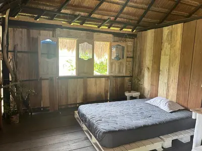 a bedroom with a bed in a wooden wall at Punta Arena EcoHostal & EcoFit - Your Eco-Friendly Oasis in Playa Punta Arena