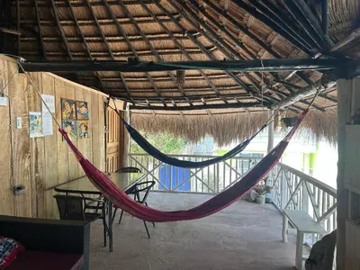 a hammock in a room with a table and chairs at Punta Arena EcoHostal & EcoFit - Your Eco-Friendly Oasis in Playa Punta Arena