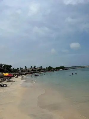 a beach with a bunch of people in the water at Punta Arena EcoHostal & EcoFit - Your Eco-Friendly Oasis 01 in Playa Punta Arena