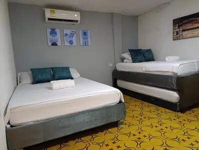 two beds in a small room with blue pillows at Casa vacacional, cerca del aeropuerto in Cartagena de Indias