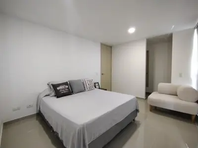 a white bedroom with a bed and a chair at Acogedor apartamento en exclusivo barrio de Barranquilla BUENAVISTA - SUNSET VIEW in Barranquilla