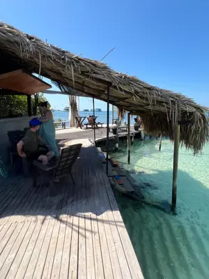 two people sitting on a wooden deck near the water at El Arca in Tintipan Island