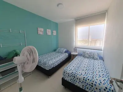 a blue room with two beds and a fan at Acogedor Apto en piso 22 vista al mar in Cartagena de Indias