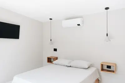a white bedroom with two beds and a tv at Gaia Casa de Mar in El Bobo