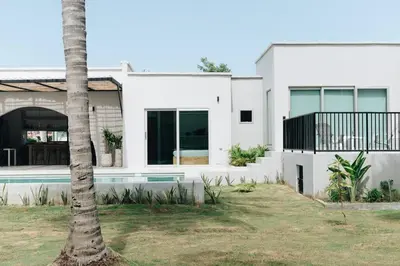 a white house with a palm tree in front of it at Gaia Casa de Mar in El Bobo