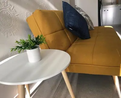 a yellow couch with a white table with a plant on it at Acogedor apartamento en Cartagena/asequible in Cartagena de Indias