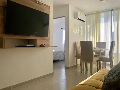 a living room with a television and a table with chairs at Acogedor apartamento en Cartagena/asequible in Cartagena de Indias