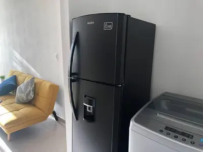 a black refrigerator in a kitchen with a couch at Acogedor apartamento en Cartagena/asequible in Cartagena de Indias