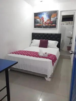 a bedroom with a bed with a picture on the wall at HOSTAL BARRANQUILLA INN in Barranquilla