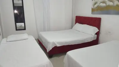 a room with two beds and a red chair at HOSTAL BARRANQUILLA INN in Barranquilla