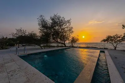 a swimming pool next to the ocean at sunset at ACASI Rustic Beach in Baru