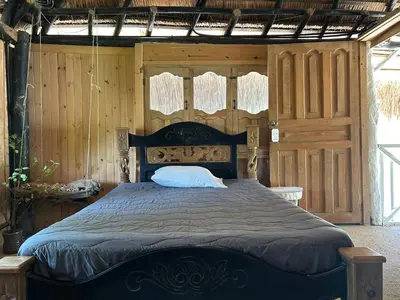 a bedroom with a large bed with wooden walls at Punta Arena EcoHostal & EcoFit in Playa Punta Arena