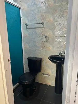 a bathroom with a black toilet and a sink at Punta Arena EcoHostal & EcoFit 01 in Playa Punta Arena