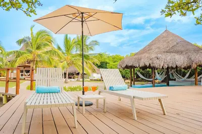 two chairs and an umbrella on a deck with a pool at U-GO Espectacular Casa en Barú con Vistas al Mar in Cartagena de Indias