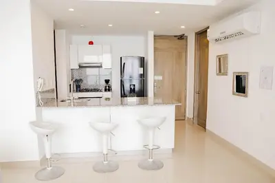 a white kitchen with stools at a counter at U-GO Morros City Bocagrande Frente al Mar in Cartagena de Indias