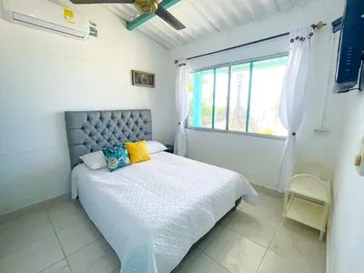 a white bedroom with a bed and a window at Cabaña Tierramia 1 in San Silvestre