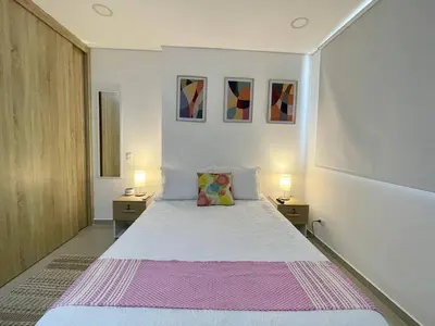 a bedroom with a white bed with two nightstands and two lamps at Moderno y amplio apartamento cerca a la playa! in Cartagena de Indias