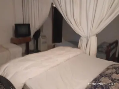 a bedroom with a white bed with curtains and a television at Hostal Sol in Cartagena de Indias