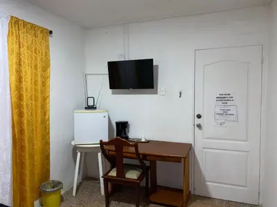 a room with a desk and a television on a wall at Habitación Cerca de aeropuerto in Cartagena de Indias