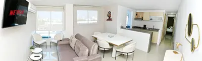 a living room with a table and chairs and a kitchen at Excelente ubicación y cómodo apto, perfecto para ti! in Barranquilla
