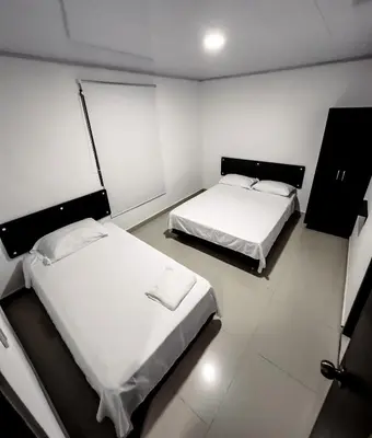 two beds in a room with white walls at Hotel bazurto plaza in Cartagena de Indias