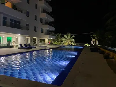a swimming pool in front of a building at night at Apartamento playa Morros, La boquilla, Cartagena de indias in Cartagena de Indias