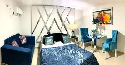 a bedroom with a bed and two blue chairs at Hotel Platinum Luxury in Barranquilla