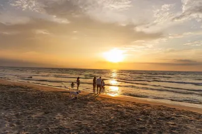 a group of people walking on the beach at sunset at Hotel Playa Palmeras Cartagena - Vía al Mar in Cartagena de Indias