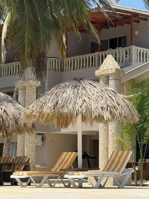 two chairs and an umbrella on a beach at Hotel Playa Palmeras Cartagena - Vía al Mar in Cartagena de Indias